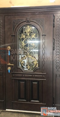 темная резная входная дверь с декоративной ковкой и стеклом